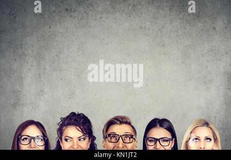 Closeup of young people heads standing near a gray concrete wall. A diverse business team and brainstorming concept Stock Photo