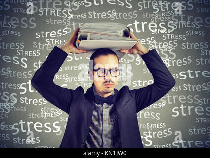 Stressed doomed business man standing with heavy folders on his head isolated on gray background Stock Photo
