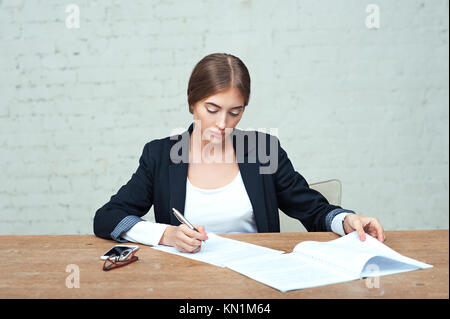 Pretty business lady working with data documents sitting at the table in office Stock Photo
