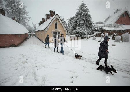 Snow in Thaxted-Met Office Severe Weather Amber Warning- Essex England, UK. 10th Dec, 2017. Heavy snow fell overnight and through the morning across parts of the UK following a 'Met Office Severe Weather Amber Warning' as Storm Caroline drags in cold air from Scandinavia as seen here in the beautiful medieval town of Thaxted in North West Essex in East Anglia, England. Walkers are seen passing by the world famous 17th and 18th century Almshouses and John Webb's Windmill from the early 19th century. Credit: BRIAN HARRIS/Alamy Live News Stock Photo
