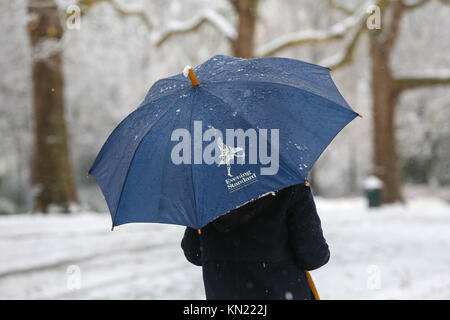Finsbury Park, North London. UK 10 Dec 2017 - A woman shelters under an Evening Standard umbrella in Finsbury Park, north London after the first snowfalls of the winter. Credit: Dinendra Haria/Alamy Live News Stock Photo