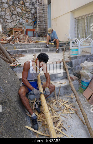 Mexican man scraping bark fron tree limbs to make stair railings ...