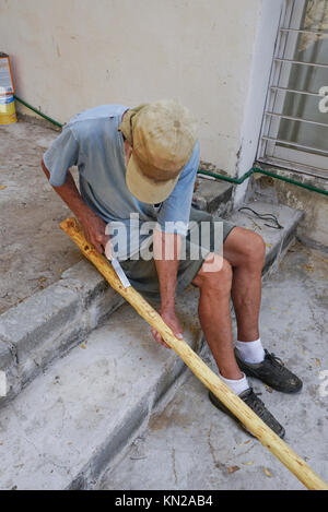 Mexican man scraping bark fron tree limbs to make stair railings ...