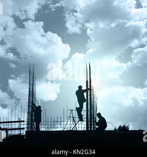 Unrecognizable silhouettes of builders against the background of a colorful sunset Stock Photo
