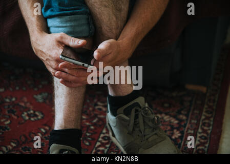 man's cross hands with smartphone close up Stock Photo