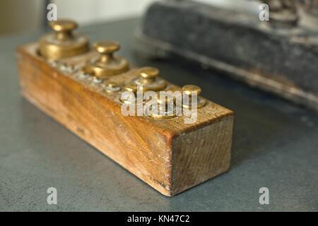 Old vintage brass weights for weighing dough in a bakery in a wooden box.