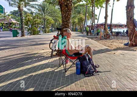 Lifestyle image of a Mature male cyclist taking a break and relaxing in a recliner chair. Pattaya Thailand, Southeast Asia. Stock Photo