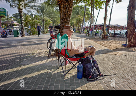 Lifestyle image of a Mature male cyclist taking a break and relaxing in a recliner chair. Pattaya Thailand, Southeast Asia. Stock Photo