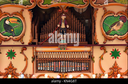 an antique, vintage, or steam powered fairground organ in brightly coloured livery and paint on display playing music to an audience of enthusiasts. Stock Photo