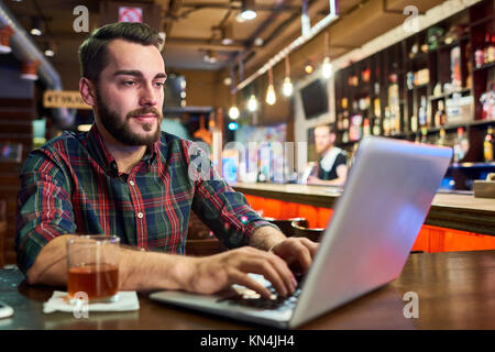 Young Man Working with Laptop in Pub Stock Photo
