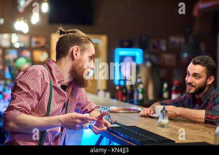Bartender Talking to Visitor at Pub Counter Stock Photo