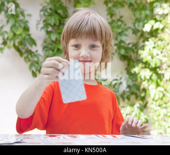Boy with Blond Hair Playing Cards Outdoors.