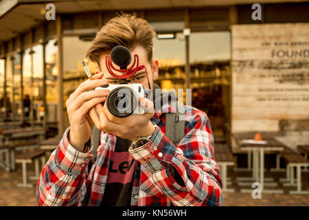 Toned Portrait of a Young Man Holding A Cigarette Smoking and Taking a Photograph Stock Photo