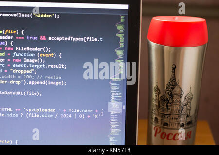 Laptop with programming web code and red capped flask aside. Travel programming concept. Stock Photo