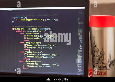 Laptop with programming web code and red capped flask aside. Travel programming concept. Stock Photo