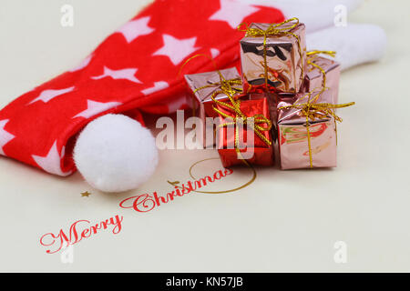 Merry Christmas card with stack of shiny presents and red Christmas hat Stock Photo