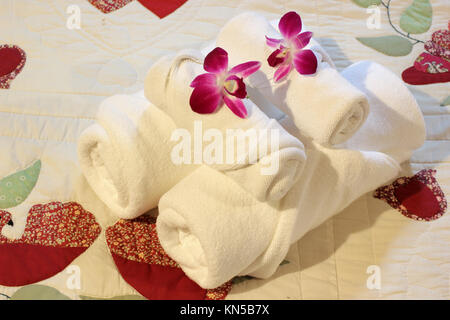 white bath towels rolled and piled on the bed Stock Photo