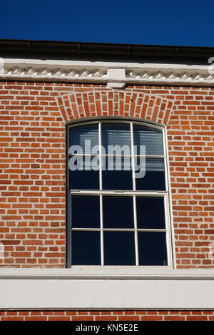 Modernised arched metal window with aluminum blinds in a red brick facade Stock Photo