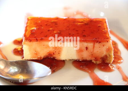 Creme caramel with strawberry jam on plate.