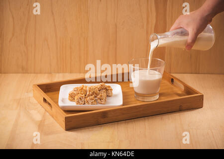 milk pour from bottle, almond candies on wooden background Stock Photo