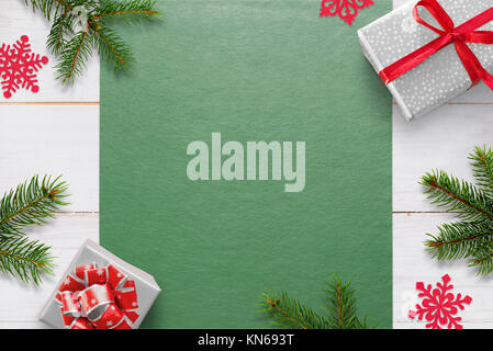 Christmas background with decorations on white wooden table and green tablecloth with free space for greeting text. Gifts, fir branches and snowflake  Stock Photo