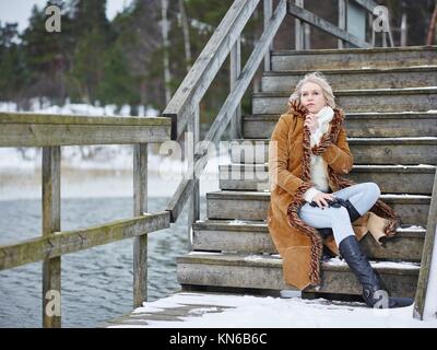 Fashionable mature adult woman wearing winter clothes and she standing next  to the fence - rural scene Stock Photo - Alamy