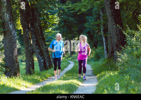 Two active seniors with a healthy lifestyle smiling while joggin Stock Photo