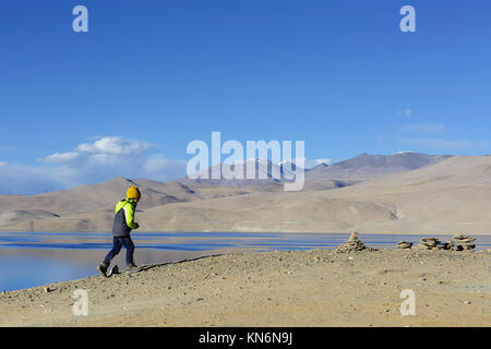 Young boy walking uphill to stone towers at lake Tso Moriri, Ladakh, Jammu and Kashmir, India. Stock Photo