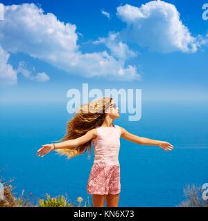 Blond girl shaking hair on air at blue Mediterranean sea tourist in Spain open hands.
