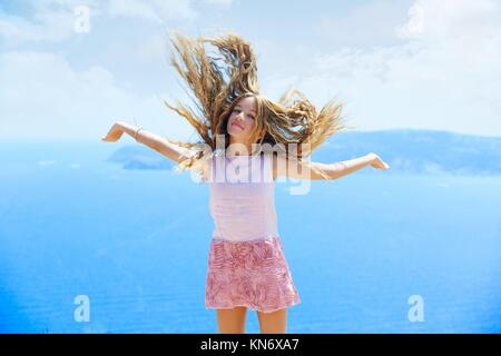 Blond girl shaking hair on air at blue Mediterranean sea tourist in Spain.