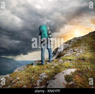 Backpacker in mountains under the thunder clouds.