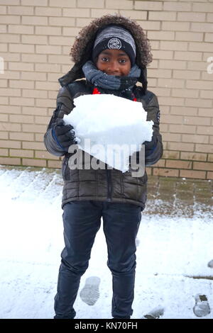 A young Afro-Caribbean boy holding a snowball in the United Kingdom  December 2017 Stock Photo