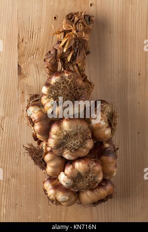 Smoked garlic braid hanging on wood.