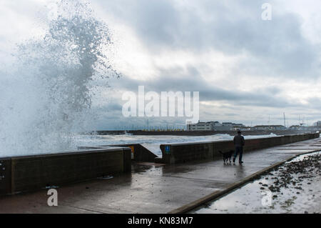 Brighton, East Sussex. 10th December 2017. UK weather. Pedestrians taking a late afternoon walk dodge huge waves crashing onto the Undercliff Walk near Brighton Marina following a day of freezing cold weather, strong winds and rain. Credit: Francesca Moore/Alamy Live News Stock Photo