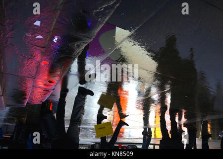 Tourists and pedestrians wander around Piccadilly Circus on a rainy evening in central London (reflection) Stock Photo