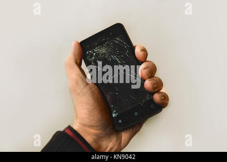 Man hand holding mobile phone with broken screen Stock Photo
