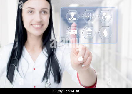 Young attractive woman doctor touching icon of media screen. Concept of innovative technologies in medicine. Stock Photo