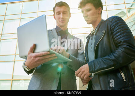 Two  Businessmen Using Laptop Outdoors Stock Photo