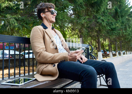 Happy Young Man in Park Listening to Music Stock Photo