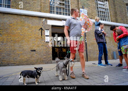 Man with two dogs looking over his shoulder on Brick Lane in Shoreditch, London, England, UK Stock Photo