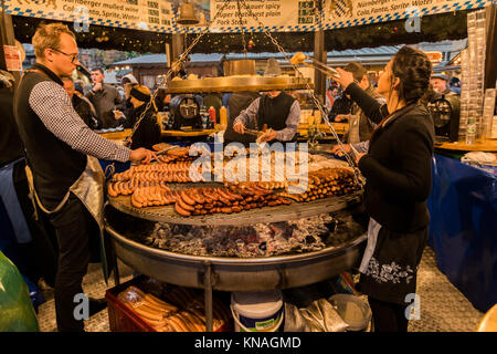 Market stall traders serve food and drink to customers at Manchester Christmas Markets Around The City, Manchester, England, UK Stock Photo