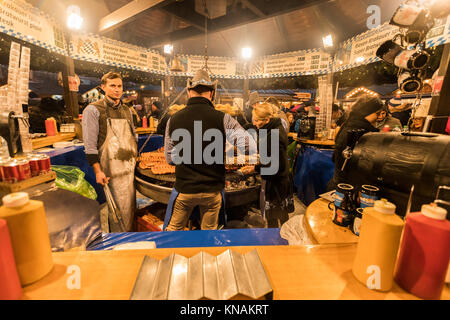Market stall traders serve food and drink to customers at Manchester Christmas Markets Around The City, Manchester, England, UK Stock Photo