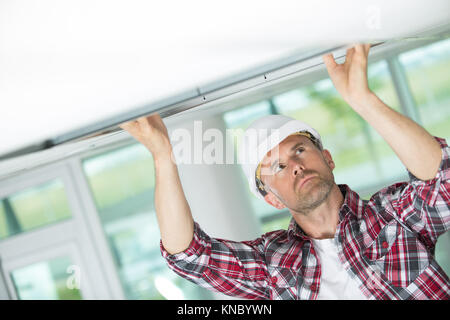 male construction worker adjusting ceiling part Stock Photo
