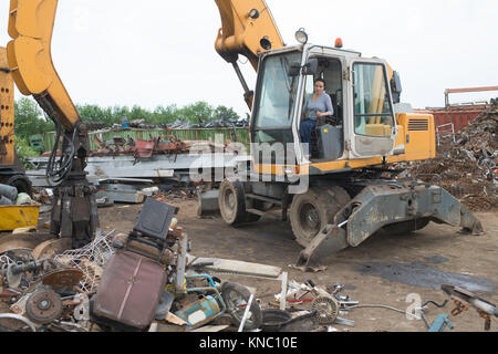 magnetic crane loading scrap metals at junkyard Stock Photo