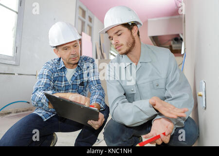 building engineers in hard hat thinking and writing on clipboard Stock Photo