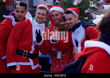 Flash mob dressed as Santa Claus walking through London, drinking and making merry for Santacon 2017 in North London, King's Cross area Stock Photo