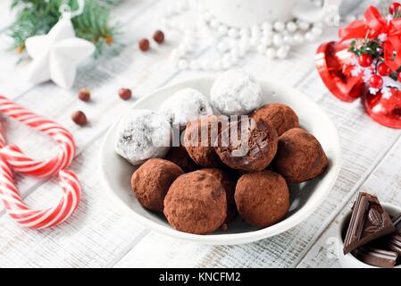 Homemade chocolate candy truffles with candy canes on white table. Christmas sweets. Closeup view Stock Photo