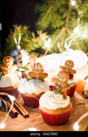 Gingerbread cupcakes, gingerbread cookies and Christmas lights. Closeup view, selective focus Stock Photo