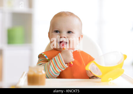 Happy infant baby boy spoon eats itself Stock Photo