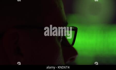 Hacker in glasses working on a computer Stock Photo